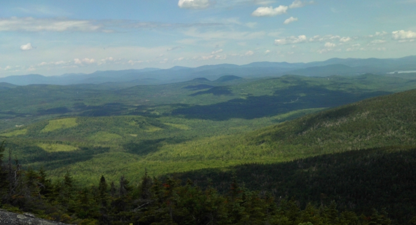 From above, a vast green mountainous landscape stretches out below